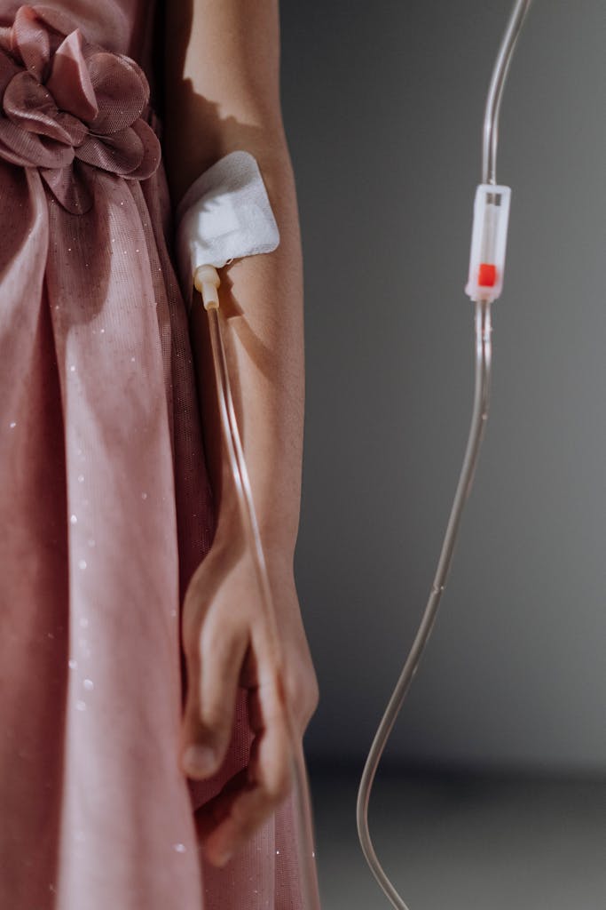 A Girl in Pink Dress with Blood Transfusion Set on Her Arm